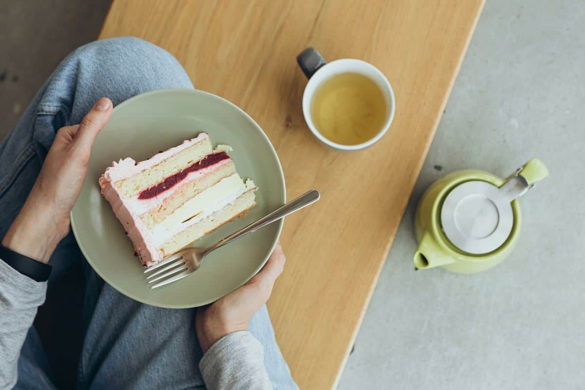 Woman eating a piece of cake and drinking tea in a cafe top view