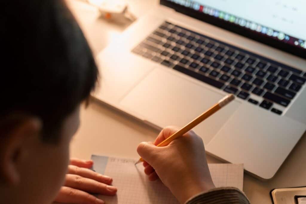 Primer plano de un niño haciendo los deberes con un portátil