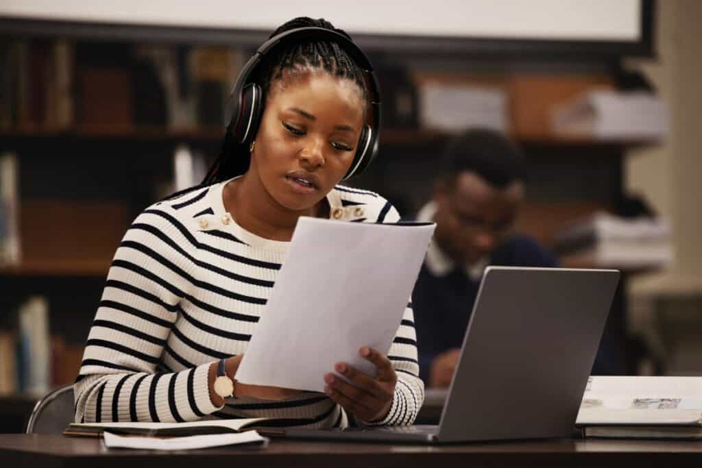 Woman documents and headphones in library for research studying