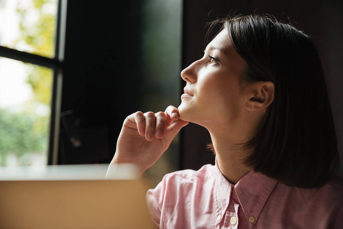 Close up image of pensive woman sitting by the table