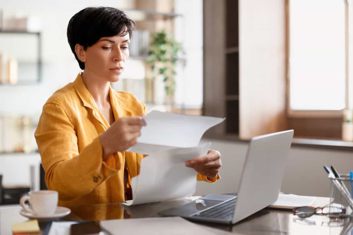 Middle aged european businesswoman reading bills