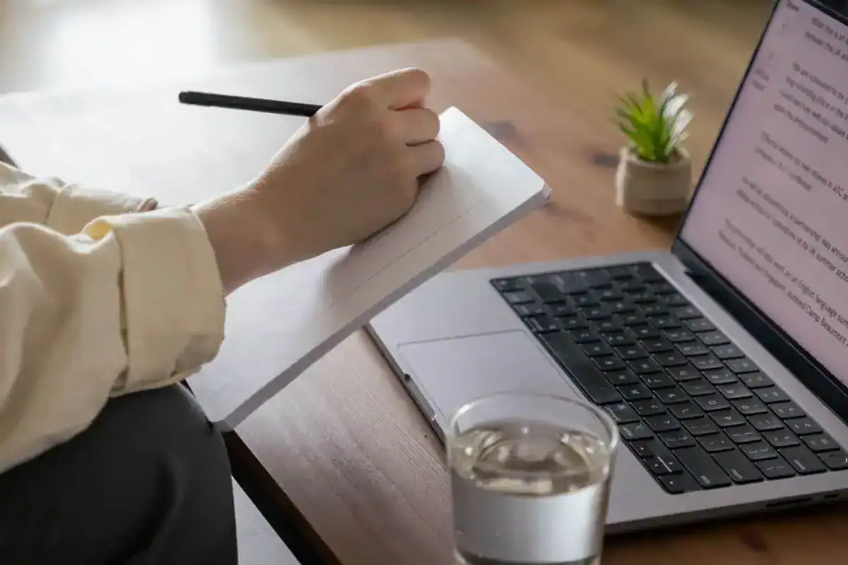 A woman sits at a laptop at an important conference taking notes