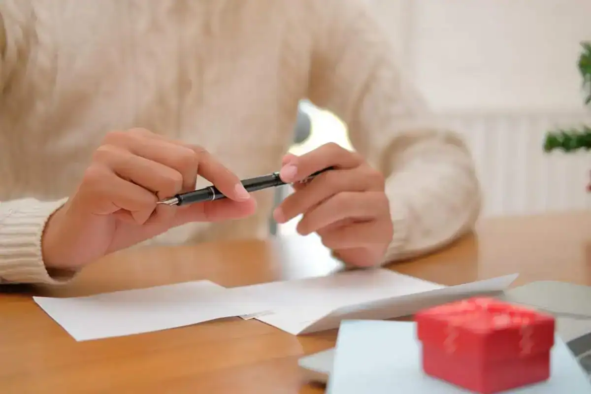 Midsection of woman holding paper while sitting on table