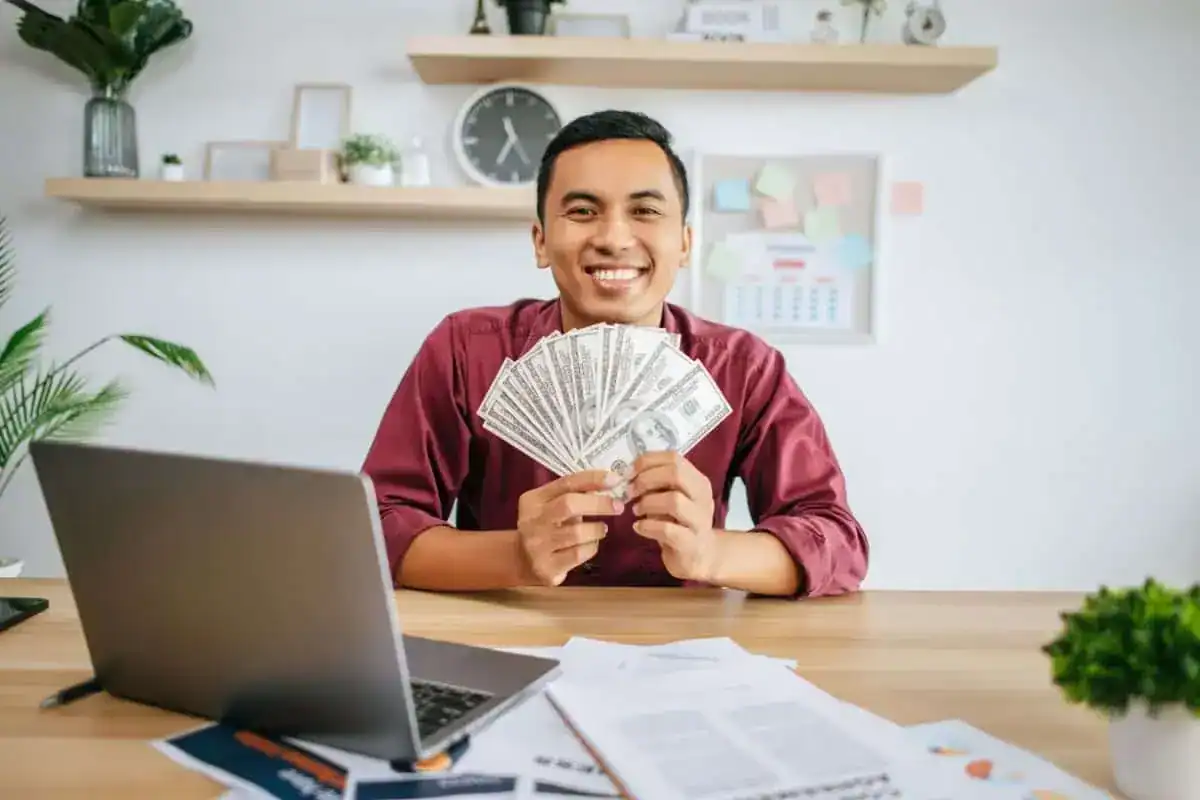 A man working in an office and holding money