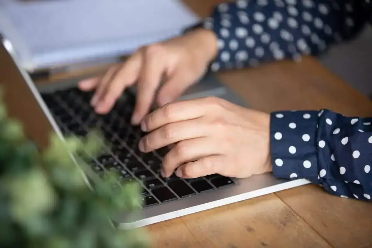 Close-up image of a hand typing on a laptop keyboard
