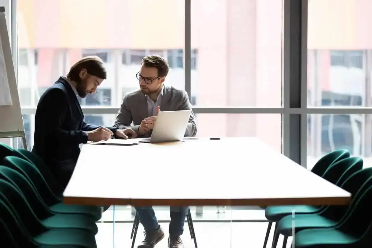 Two confident male partners signing agreement at negotiations