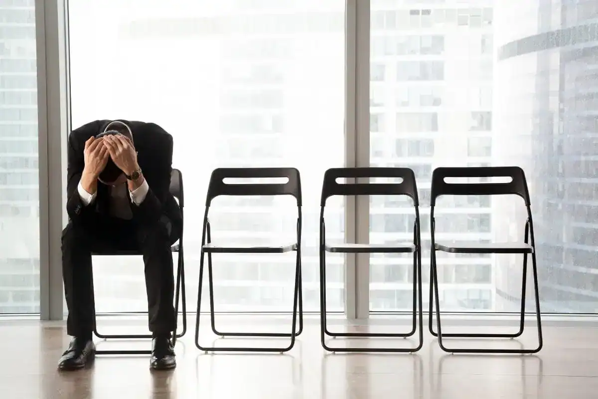 Stressed upset businessman sitting on chair in waiting room