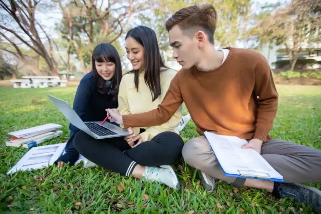 Students studying while sitting on grass at park