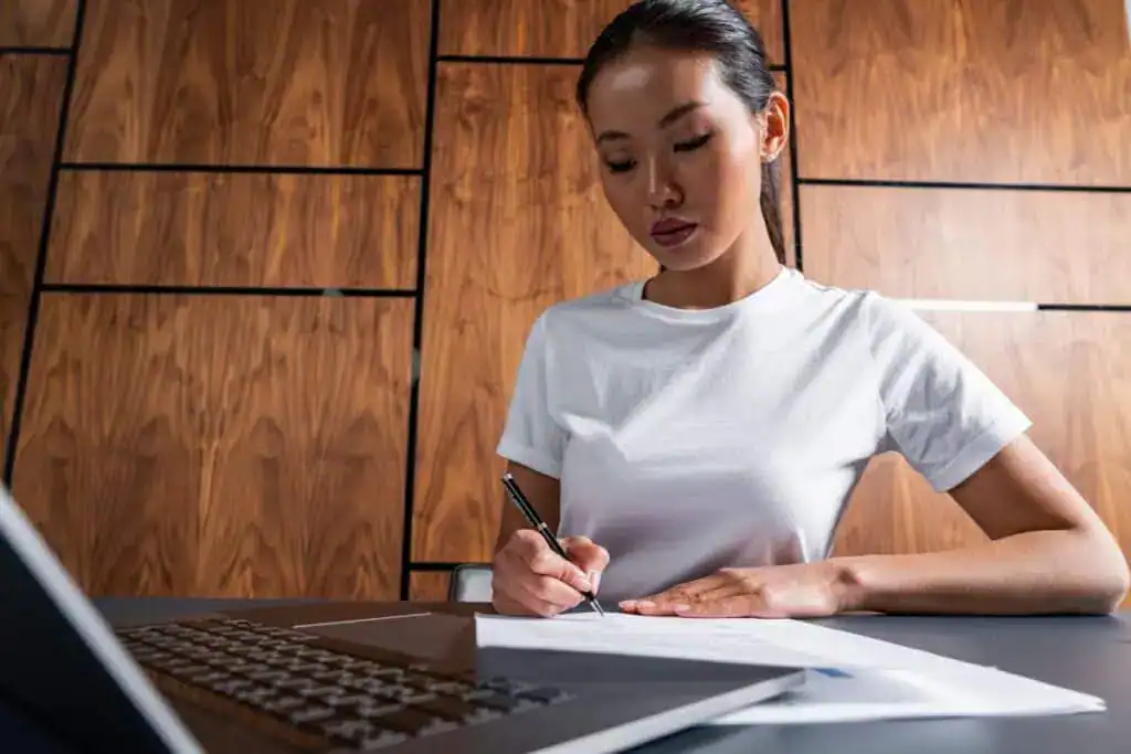 Serious asian woman signing document