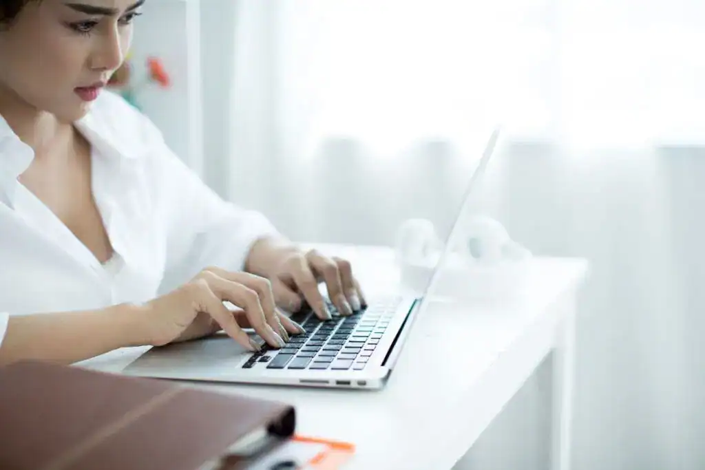 Beautiful young woman working on her laptop in her room