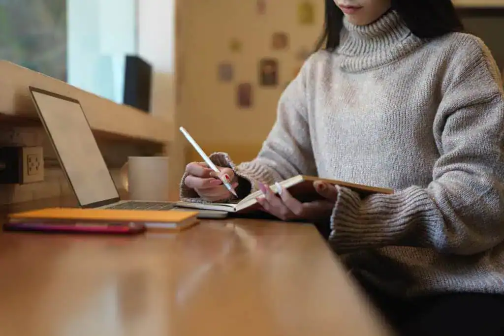 Cropped shot of female taking note while working with mock up laptop
