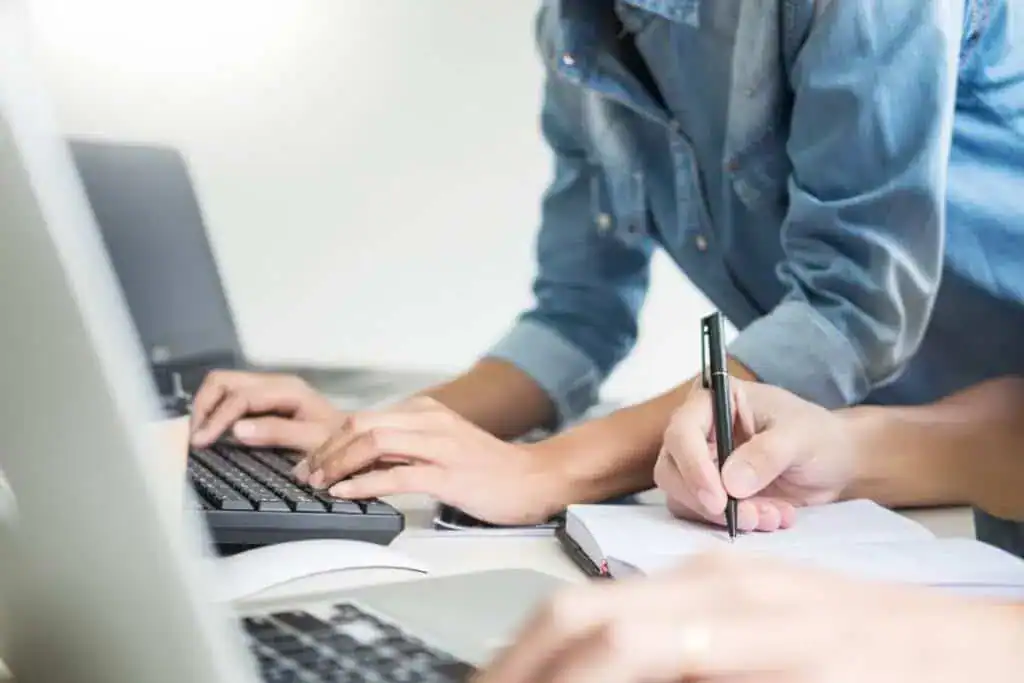 Midsection of colleagues using laptops in office