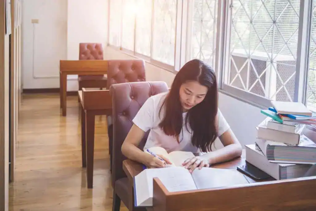 Young woman studying on table in library