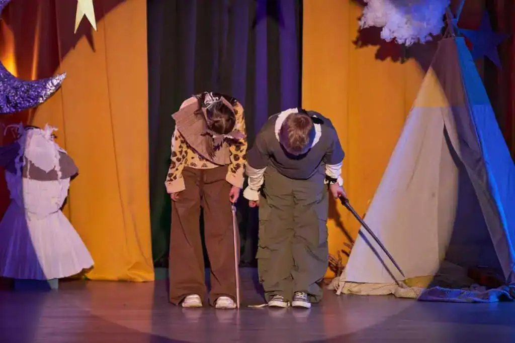 Two kids with swords bowing after play staged in childrens theater