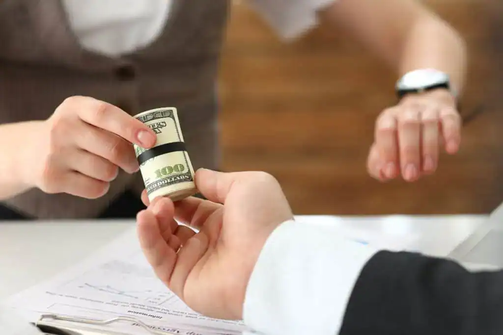 Businessman gives a cutlet from money to a woman in the form of a salary
