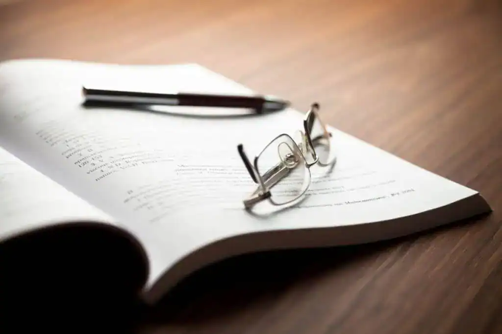 Reading glasses, pen and open book