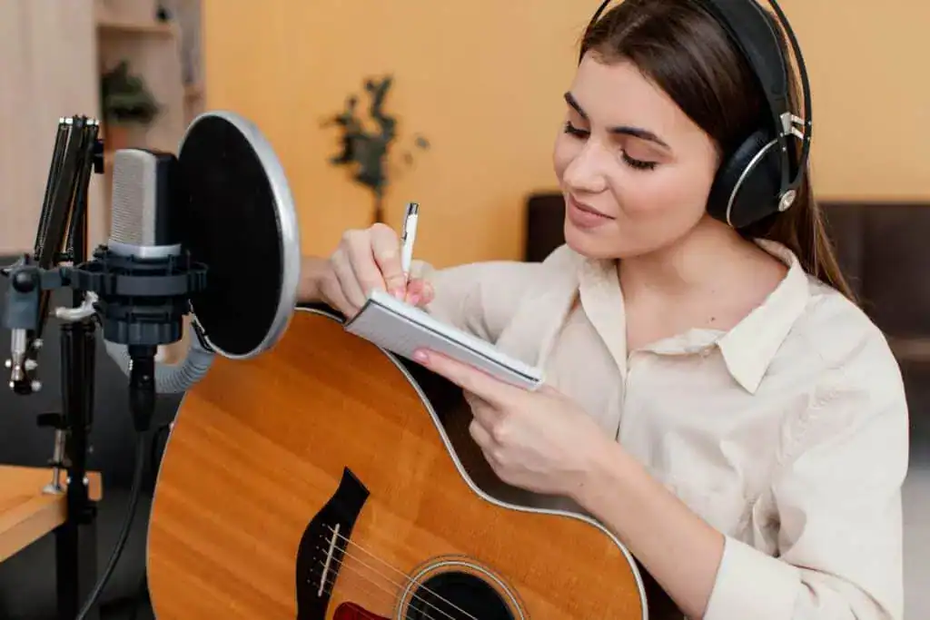 Female musician at home writing song while playing acoustic guitar
