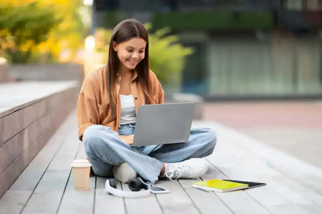 Positive student interacts with laptop at unpopulated campus