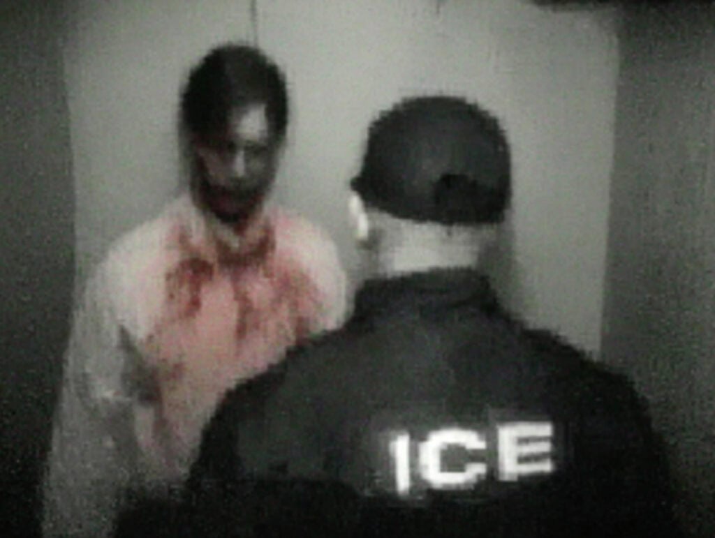 Ich habe 5 AI-Bilddetektoren getestet. Dies sind die besten im Jahr 2026: 17 Ein unscharfes Foto, das einen Mann mit einem rot gefärbten Hemd zeigt, der vor einer Person steht.